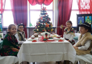 uczniowie w góralskich strojach przy stole wigilijnym