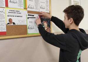 uczeń przypinający informację na tablicy korkowej