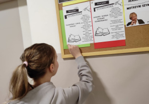 uczennica przypinająca informację na tablicy korkowej